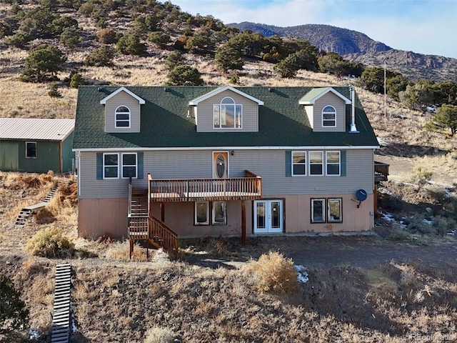 view of front of house with a deck with mountain view, stairs, and french doors