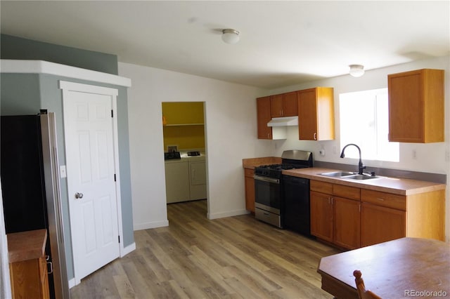 179 13th Ave, Cedaredge, CO 81413 - kitchen with under cabinet range hood, a sink, washing machine and clothes dryer, stainless steel appliances, and light wood-type flooring