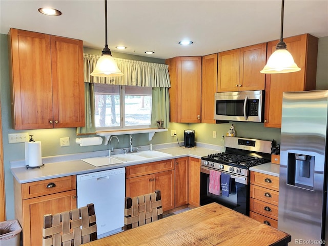 kitchen with hanging light fixtures, light countertops, appliances with stainless steel finishes, and a sink