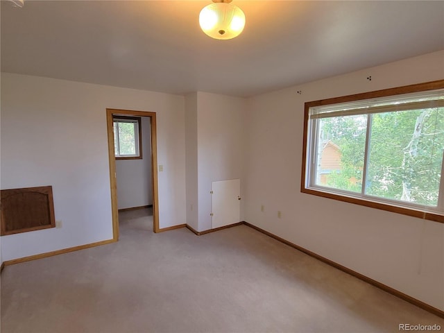 unfurnished room featuring baseboards and light colored carpet