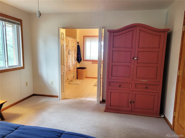 unfurnished bedroom featuring light colored carpet, baseboards, and ensuite bathroom