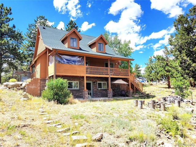 rear view of house featuring a wooden deck, brick siding, and stairs