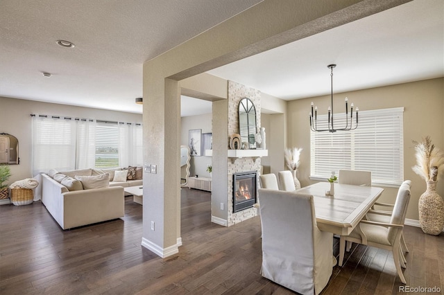 14807 Haley Ave, Parker, CO 80134 - dining space with a textured ceiling, dark wood-style flooring, baseboards, a stone fireplace, and a chandelier
