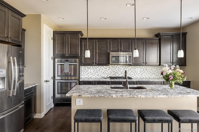 14807 Haley Ave, Parker, CO 80134 - kitchen with stainless steel appliances, a kitchen bar, a sink, and dark wood-type flooring