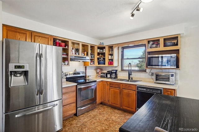 kitchen with appliances with stainless steel finishes, backsplash, track lighting, exhaust hood, and sink