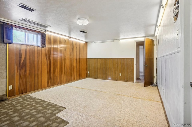 spare room featuring a textured ceiling and wooden walls