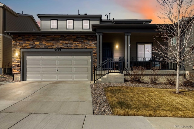 view of front of home with concrete driveway, a garage, covered porch, and stone siding