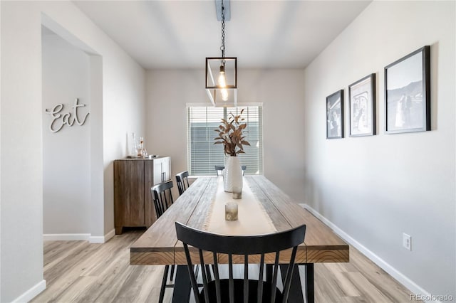 dining space with light wood-style flooring and baseboards