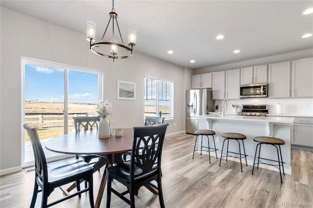 dining room featuring recessed lighting, light wood-style floors, baseboards, and a chandelier