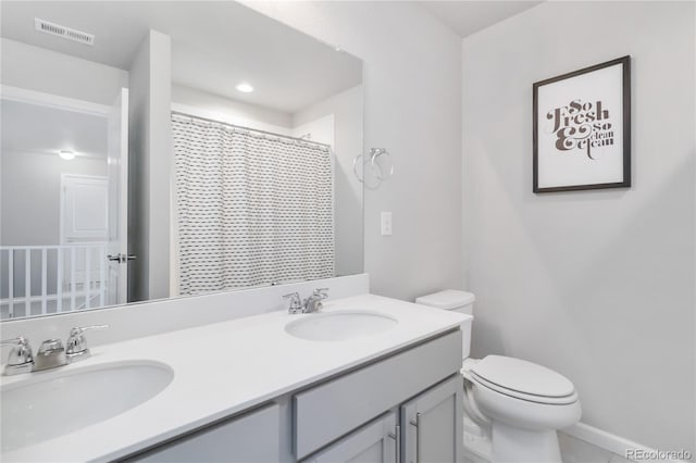 full bathroom with double vanity, toilet, visible vents, and a sink