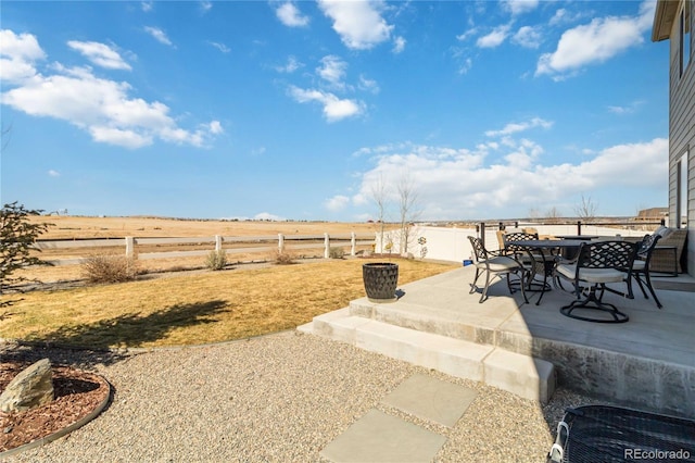 view of patio with outdoor dining space, a rural view, and a fenced backyard