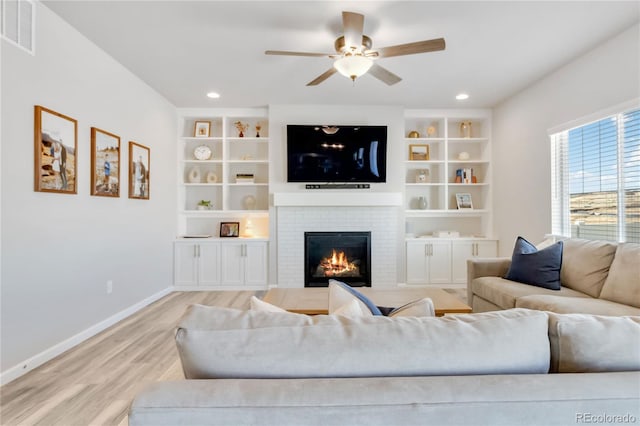living area featuring ceiling fan, visible vents, a fireplace, baseboards, and light wood-style floors