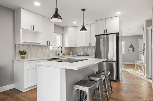 kitchen with baseboards, a center island, tasteful backsplash, a sink, and appliances with stainless steel finishes