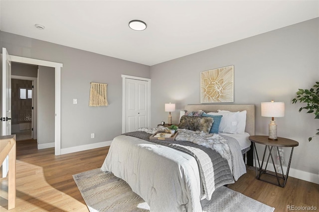 bedroom featuring baseboards, wood finished floors, and a closet
