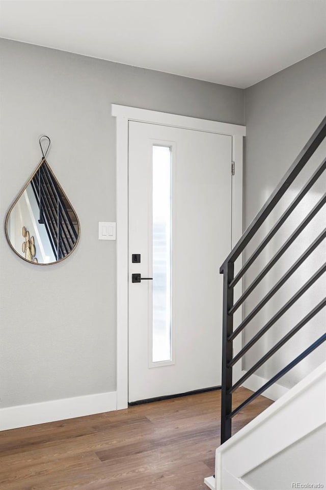 foyer with baseboards, wood finished floors, and stairway