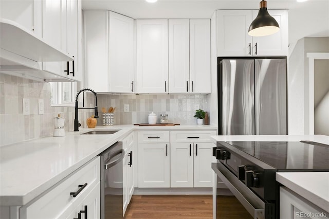 kitchen with a sink, appliances with stainless steel finishes, decorative backsplash, and light countertops
