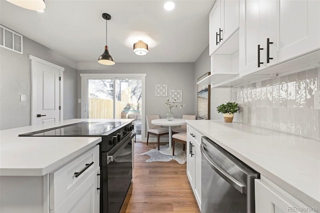 kitchen featuring light countertops, black electric range, wood finished floors, stainless steel dishwasher, and visible vents