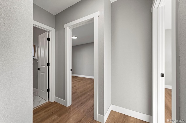 corridor with baseboards and wood finished floors