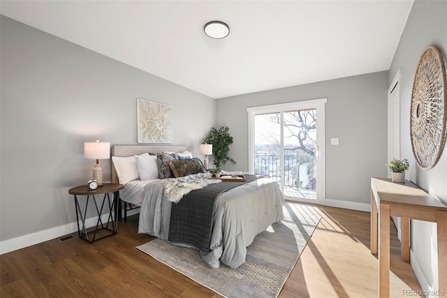 bedroom featuring access to outside, baseboards, wood finished floors, and visible vents