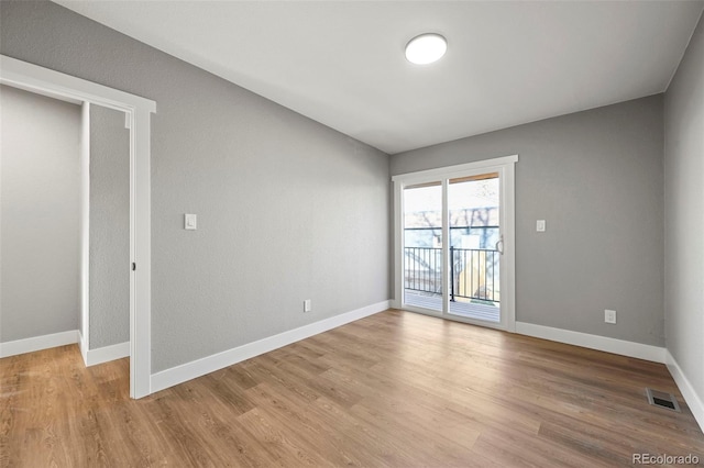 empty room with baseboards, light wood-style flooring, and visible vents