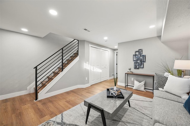 living room with visible vents, stairs, wood finished floors, baseboards, and recessed lighting
