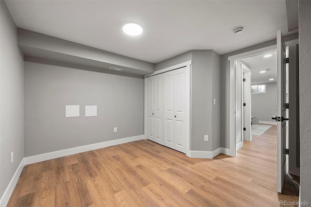 unfurnished bedroom with a closet, baseboards, and light wood-style floors