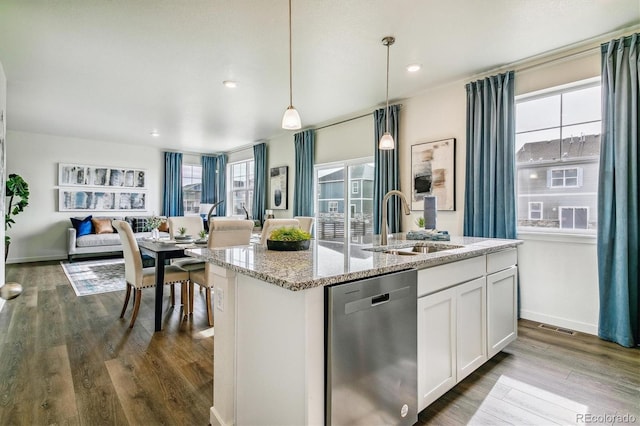 kitchen featuring dishwasher, open floor plan, dark wood-type flooring, a kitchen island with sink, and a sink