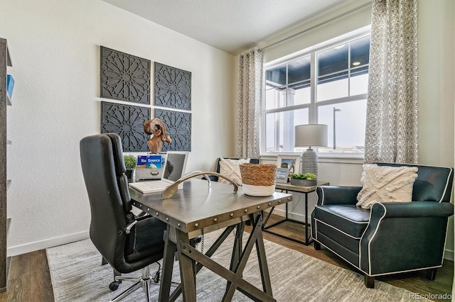 office with baseboards, wood finished floors, and a textured wall