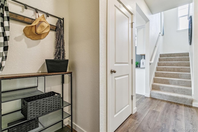 staircase with a textured wall, wood finished floors, and baseboards