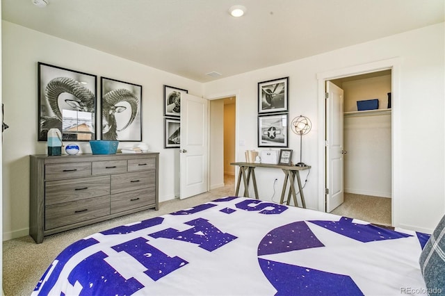 bedroom featuring light carpet, baseboards, and a walk in closet