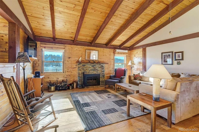 living room featuring a stone fireplace, a wealth of natural light, light hardwood / wood-style floors, and wood walls