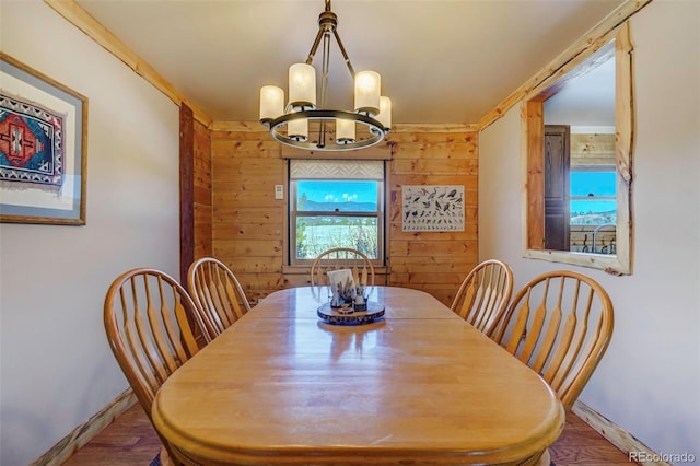 dining space featuring a notable chandelier, wood walls, and wood-type flooring