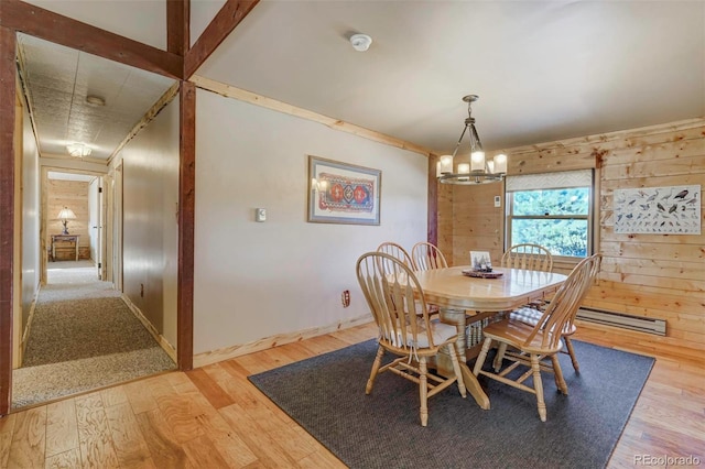 dining room featuring light hardwood / wood-style floors, baseboard heating, wooden walls, and an inviting chandelier