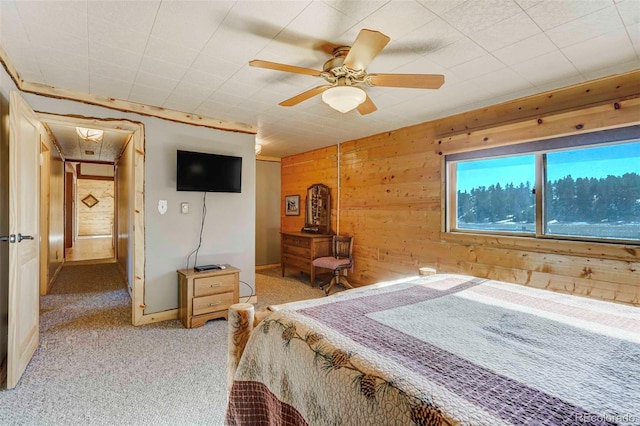 carpeted bedroom featuring ceiling fan and wooden walls