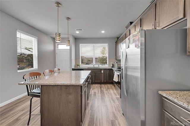 847 Great Plains Ave, Berthoud, CO 80513 - kitchen featuring stainless steel appliances, a kitchen bar, light wood-type flooring, a kitchen island, and recessed lighting