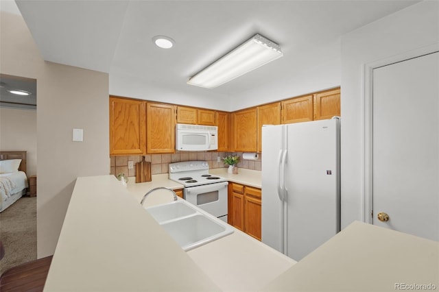 kitchen featuring backsplash, white appliances, and kitchen peninsula