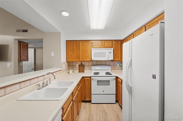 kitchen with sink, backsplash, kitchen peninsula, light hardwood / wood-style floors, and white appliances