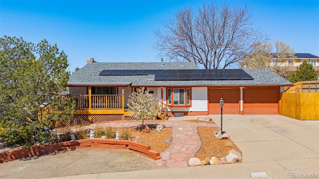 2115 Rangeview Dr, Pueblo, CO 81008 - ranch-style home with roof with shingles, roof mounted solar panels, concrete driveway, and covered porch