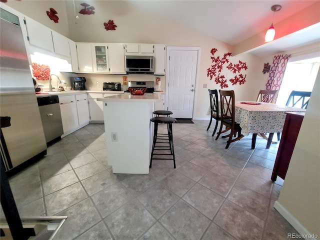 2115 Rangeview Dr, Pueblo, CO 81008 - kitchen featuring appliances with stainless steel finishes, vaulted ceiling, a kitchen island, light countertops, and white cabinets