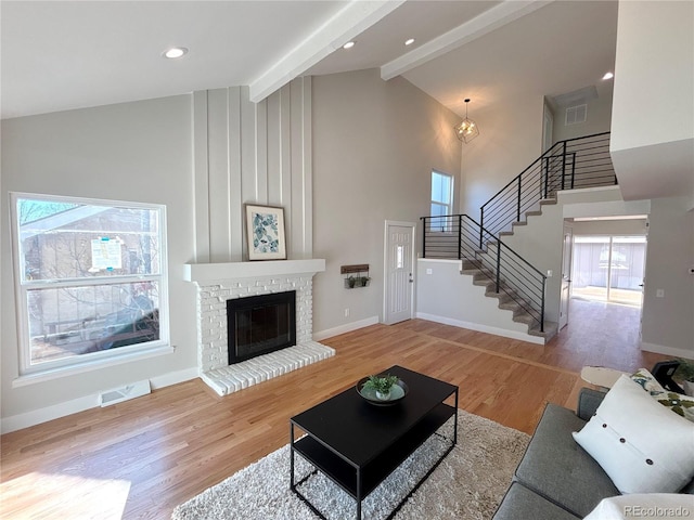 living room with high vaulted ceiling, a brick fireplace, hardwood / wood-style floors, and beam ceiling