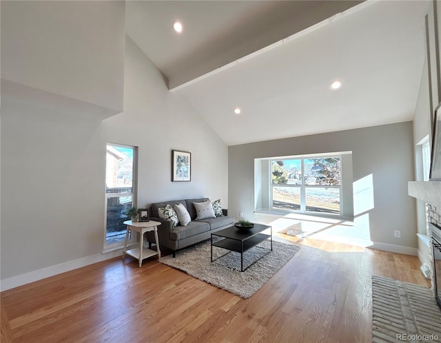 living room featuring a brick fireplace, high vaulted ceiling, light hardwood / wood-style floors, and beamed ceiling