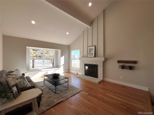 living room with hardwood / wood-style flooring, high vaulted ceiling, a brick fireplace, and beamed ceiling