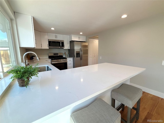 kitchen with sink, kitchen peninsula, white cabinets, and appliances with stainless steel finishes