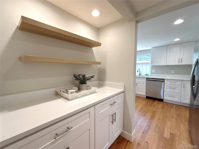 kitchen with white cabinetry, stainless steel appliances, sink, and light wood-type flooring