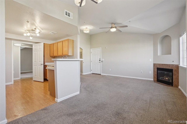 5726 N Genoa Way Unit 301, Aurora, CO 80019 - kitchen with a ceiling fan, a tiled fireplace, light countertops, vaulted ceiling, and light carpet