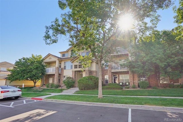 5726 N Genoa Way Unit 301, Aurora, CO 80019 - view of front of house with brick siding, a balcony, uncovered parking, and a front yard
