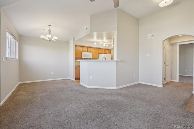 5726 N Genoa Way Unit 301, Aurora, CO 80019 - unfurnished living room with arched walkways, vaulted ceiling, a chandelier, ceiling fan, and light colored carpet