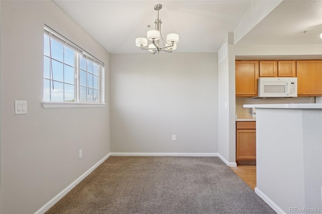 5726 N Genoa Way Unit 301, Aurora, CO 80019 - kitchen featuring white microwave, light colored carpet, a chandelier, pendant lighting, and light countertops