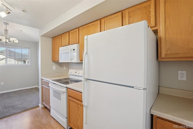 5726 N Genoa Way Unit 301, Aurora, CO 80019 - kitchen with white appliances, a chandelier, light countertops, hanging light fixtures, and light wood-style flooring