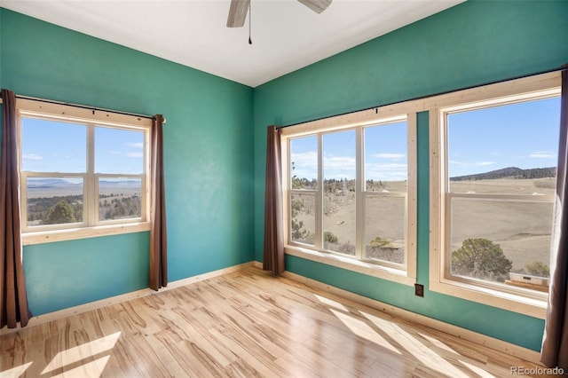 empty room featuring a healthy amount of sunlight, ceiling fan, and light hardwood / wood-style floors